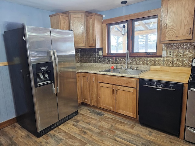 kitchen featuring dark wood-style floors, black dishwasher, visible vents, a sink, and stainless steel fridge with ice dispenser