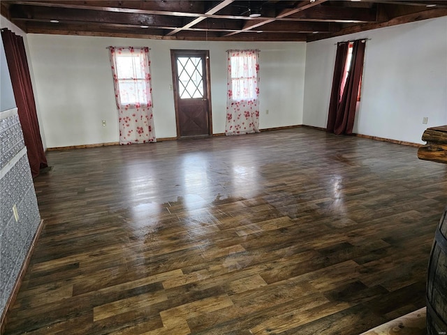 interior space with baseboards, dark wood-type flooring, and beamed ceiling