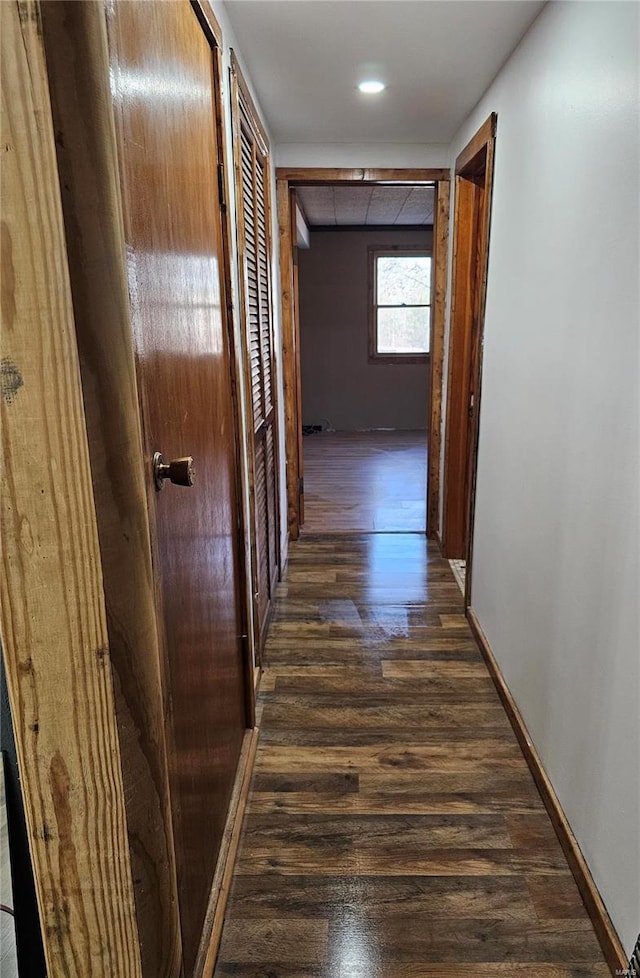 corridor with dark wood finished floors and baseboards