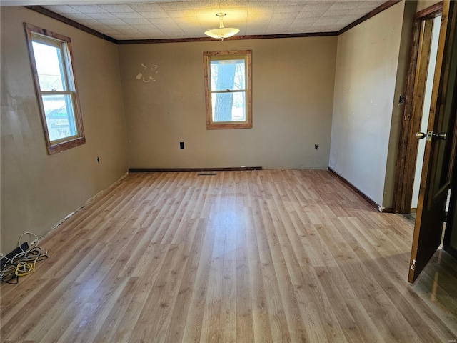 empty room with ornamental molding, wood finished floors, and visible vents