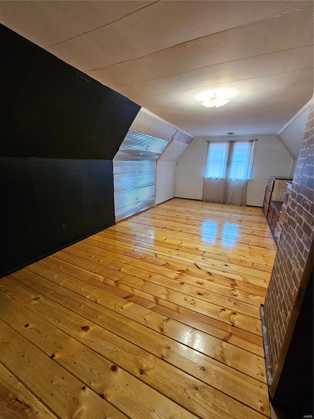 additional living space with lofted ceiling and hardwood / wood-style flooring