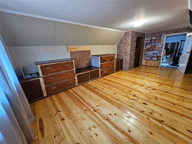 bonus room featuring lofted ceiling, brick wall, and light wood-style floors