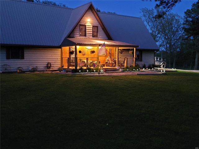 back of property featuring a porch, metal roof, and a yard