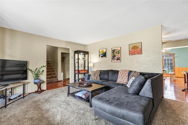 living room featuring stairs, carpet floors, and a textured ceiling