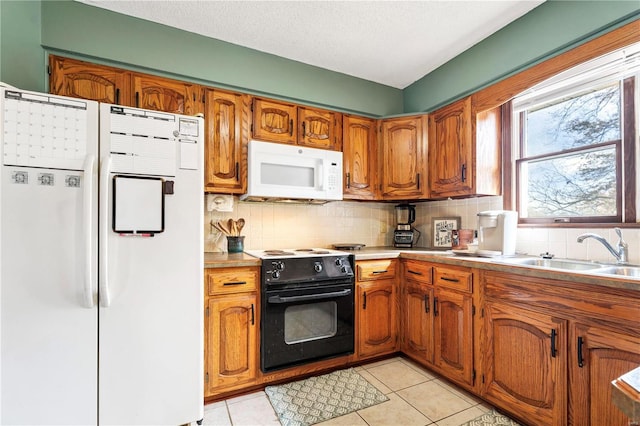 kitchen with brown cabinets, white appliances, light countertops, and a sink