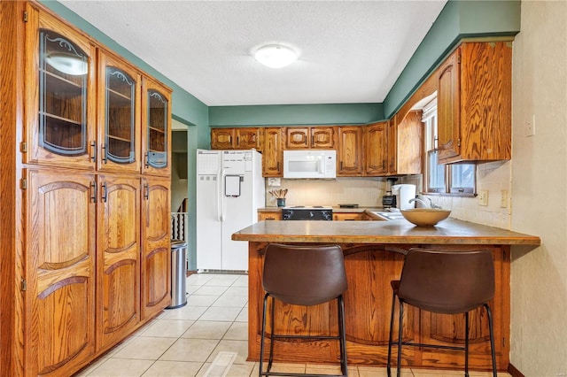 kitchen with brown cabinets, white appliances, decorative backsplash, and a sink