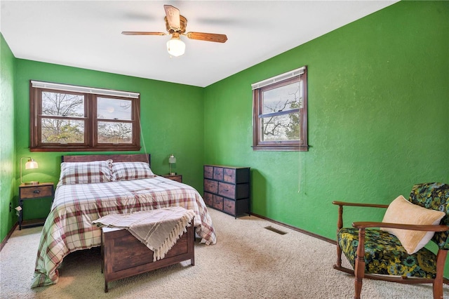 bedroom featuring ceiling fan, a textured wall, carpet flooring, and visible vents