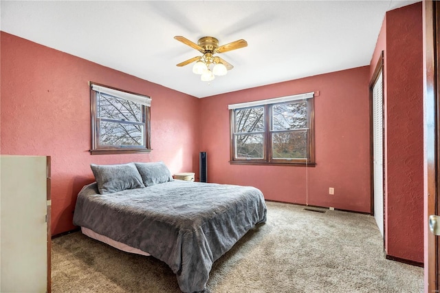 carpeted bedroom featuring visible vents and a ceiling fan