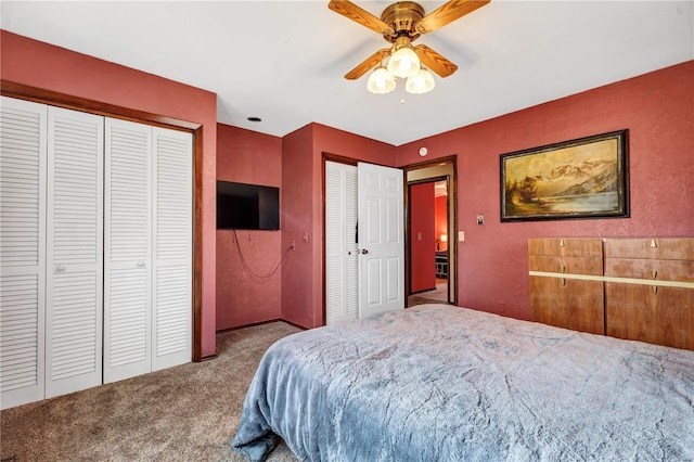 carpeted bedroom with ceiling fan and multiple closets