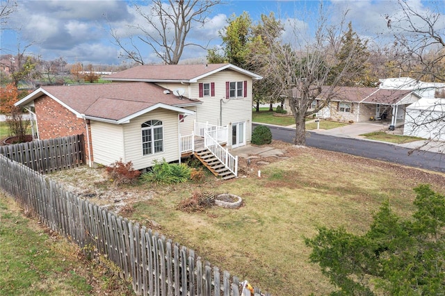 view of front facade with driveway, a front lawn, roof with shingles, and fence