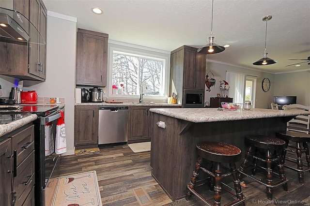 kitchen featuring a breakfast bar, light countertops, stainless steel dishwasher, dark wood-type flooring, and dark brown cabinets