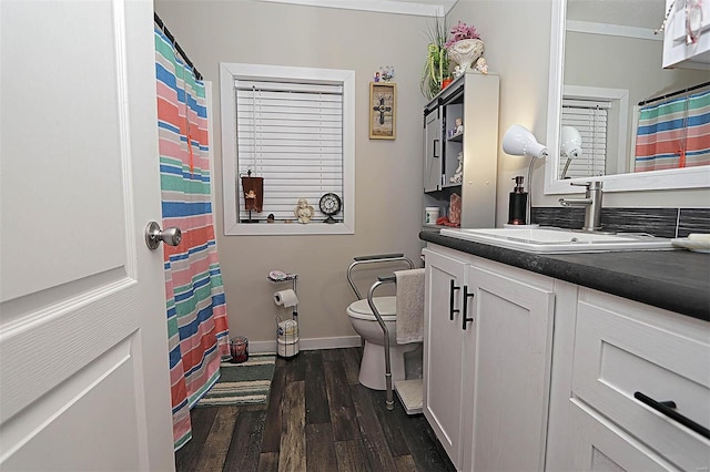 bathroom with curtained shower, toilet, vanity, wood finished floors, and baseboards