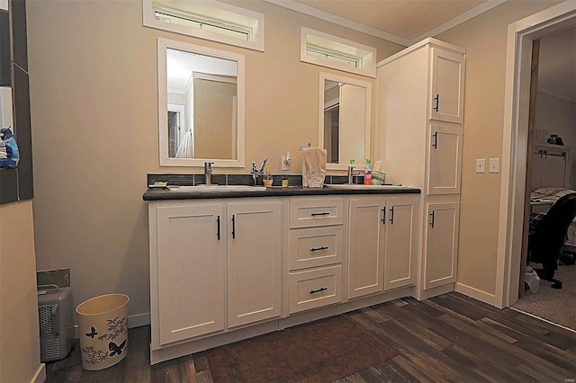 bathroom featuring double vanity, ornamental molding, a sink, wood finished floors, and baseboards