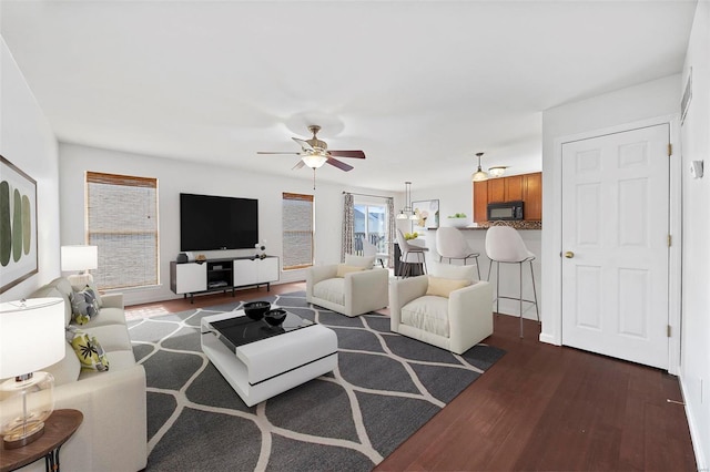 living room featuring ceiling fan and dark wood-type flooring