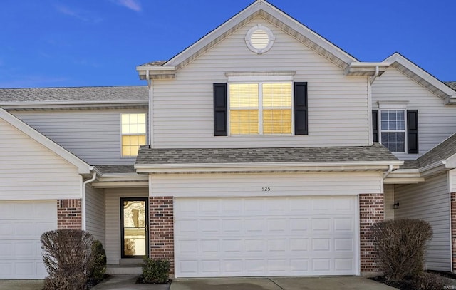 traditional-style home with an attached garage, driveway, brick siding, and a shingled roof