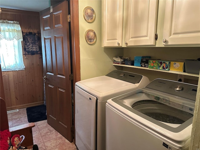 laundry area with cabinet space, visible vents, wood walls, and independent washer and dryer