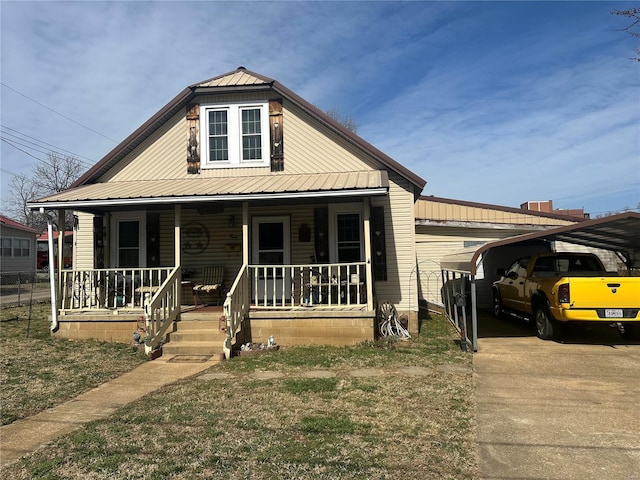 view of front facade with a detached carport, a porch, metal roof, and driveway