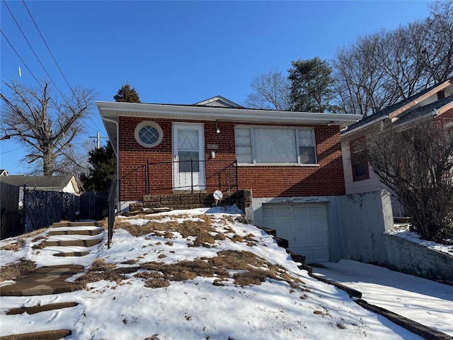 bungalow with a garage, brick siding, and fence