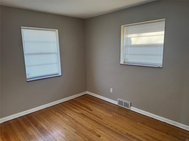 unfurnished room with light wood-style floors, baseboards, and visible vents