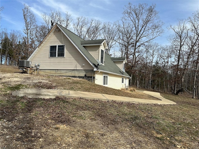 view of side of home featuring central air condition unit and a shingled roof