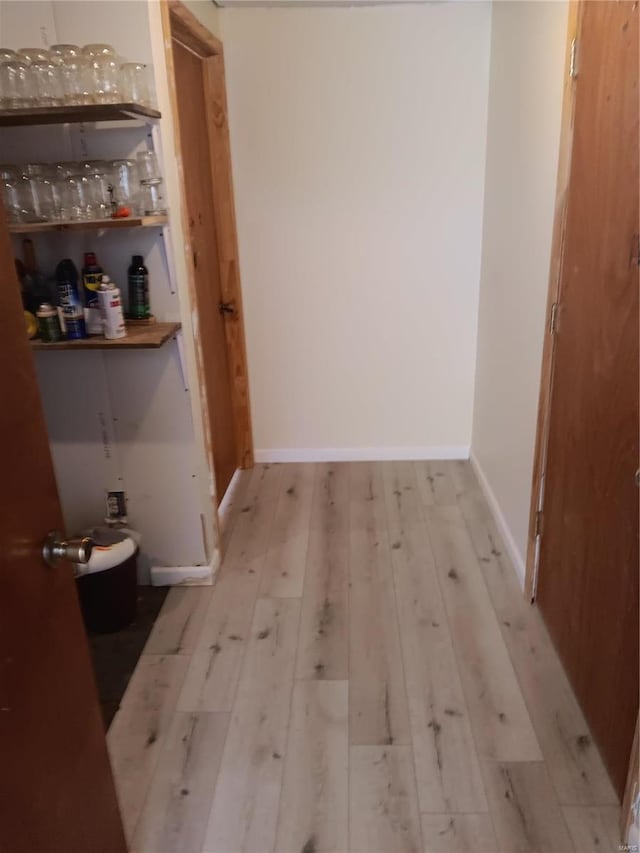 hall with wood-type flooring and baseboards