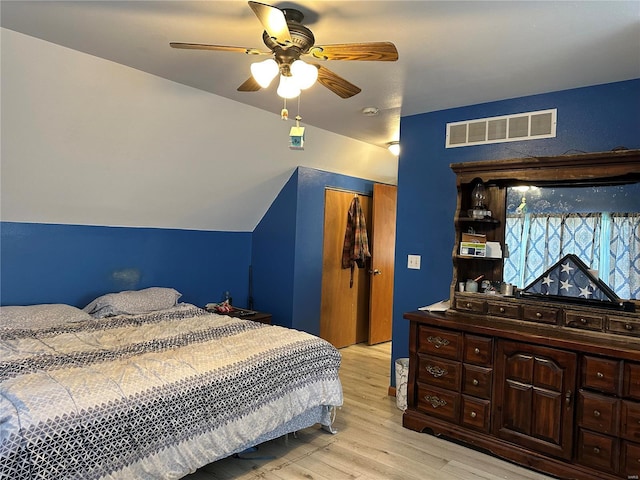 bedroom with ceiling fan, light wood-style flooring, visible vents, vaulted ceiling, and a closet