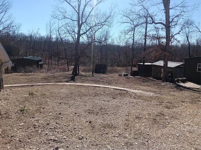 view of yard featuring an outdoor structure and a wooded view