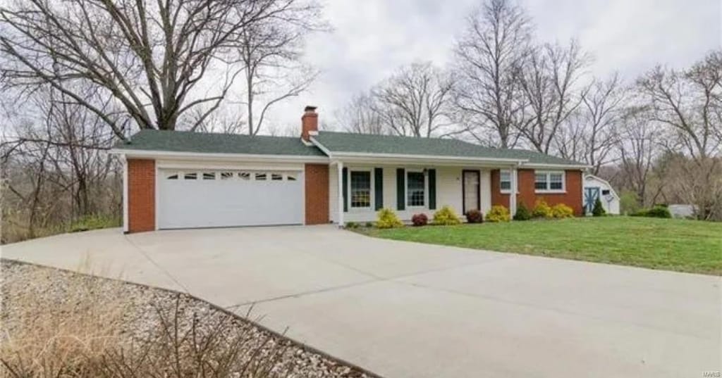 ranch-style home featuring brick siding, a chimney, concrete driveway, an attached garage, and a front lawn