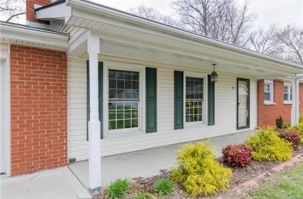 view of exterior entry featuring a porch and brick siding