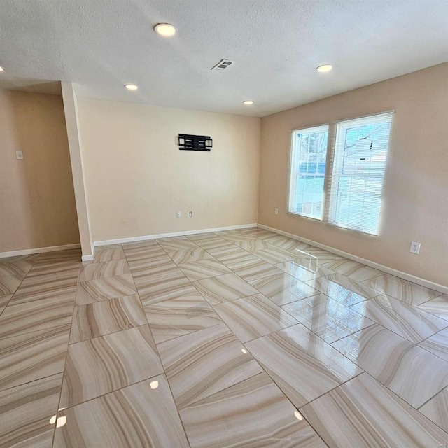 spare room with recessed lighting, visible vents, a textured ceiling, and baseboards