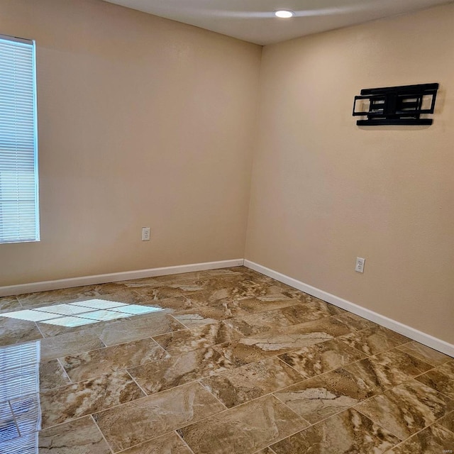 spare room featuring stone finish floor and baseboards