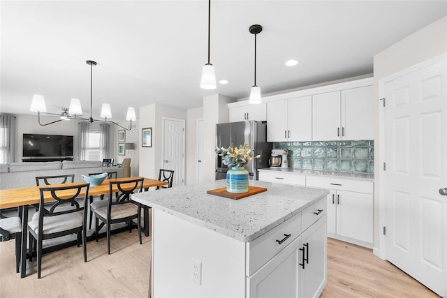 kitchen featuring freestanding refrigerator, a center island, white cabinets, and open floor plan