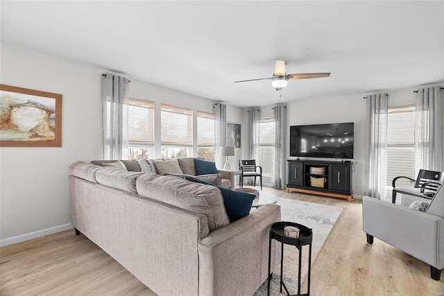 living room featuring light wood-type flooring, a ceiling fan, and baseboards