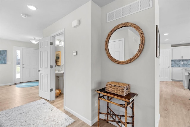 corridor with recessed lighting, baseboards, visible vents, and light wood finished floors