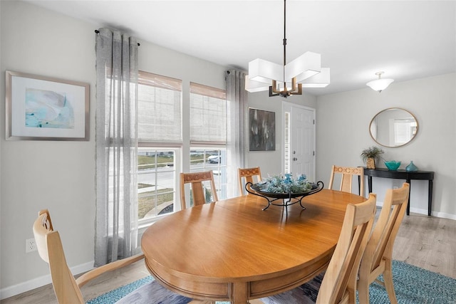 dining room with a notable chandelier, baseboards, and light wood-style floors