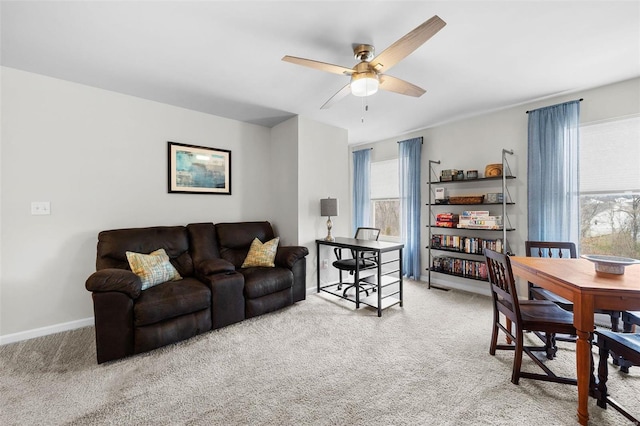 living area featuring carpet floors, plenty of natural light, baseboards, and a ceiling fan