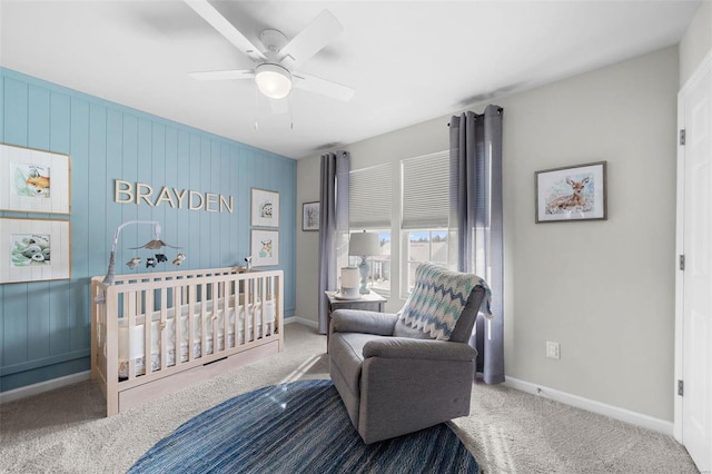 bedroom featuring a ceiling fan, carpet flooring, a crib, and baseboards