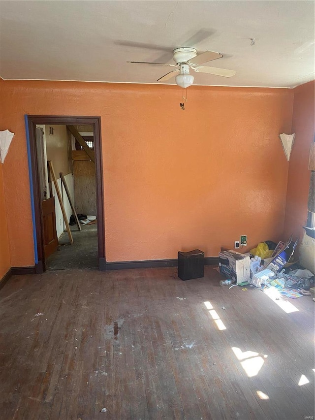 unfurnished room featuring baseboards, a ceiling fan, and dark wood-type flooring