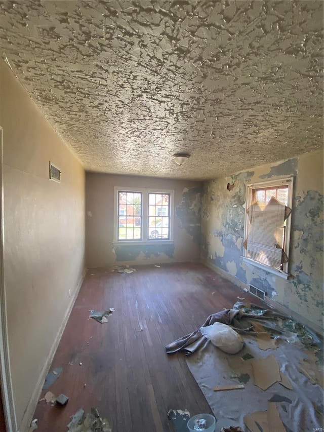 spare room featuring hardwood / wood-style floors, visible vents, and baseboards