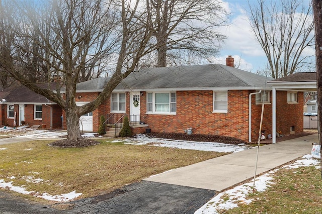 ranch-style home with driveway, a chimney, a lawn, and brick siding