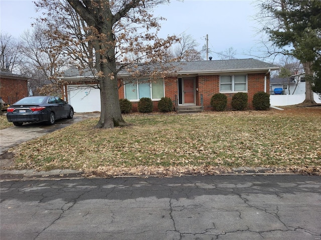 view of front of home with brick siding, driveway, and a front lawn