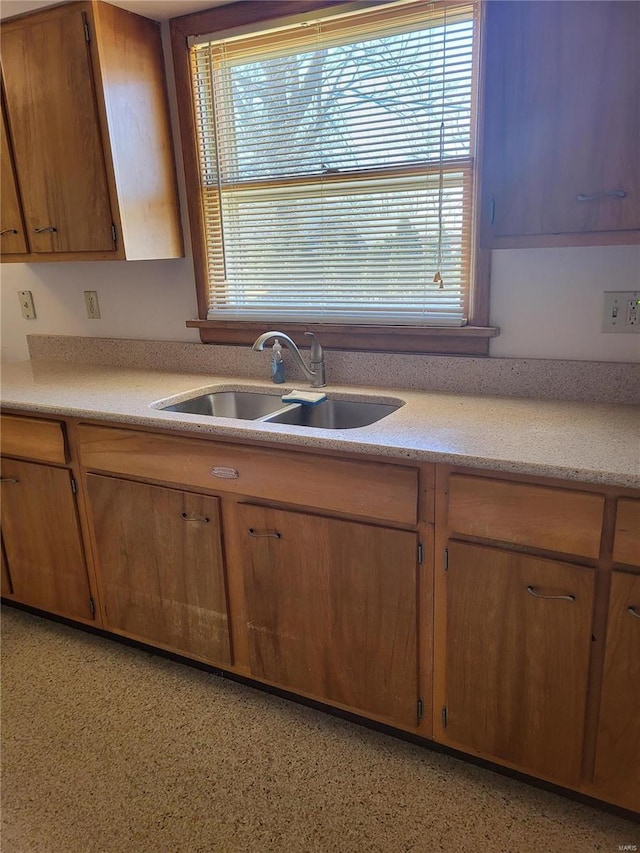 kitchen featuring brown cabinetry, a healthy amount of sunlight, light countertops, and a sink