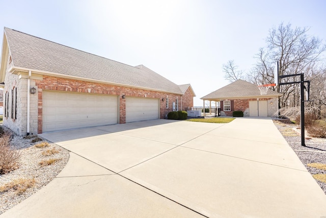 view of home's exterior featuring brick siding, an attached garage, concrete driveway, and roof with shingles