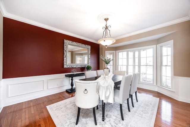 dining area with hardwood / wood-style floors, a wainscoted wall, and ornamental molding