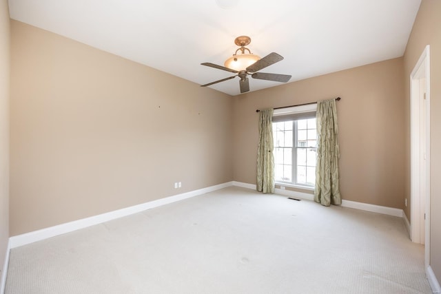 empty room with light carpet, visible vents, ceiling fan, and baseboards