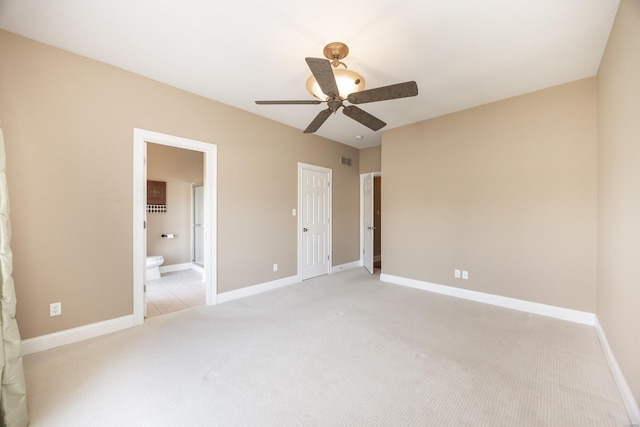 unfurnished bedroom featuring visible vents, baseboards, ceiling fan, ensuite bathroom, and light colored carpet