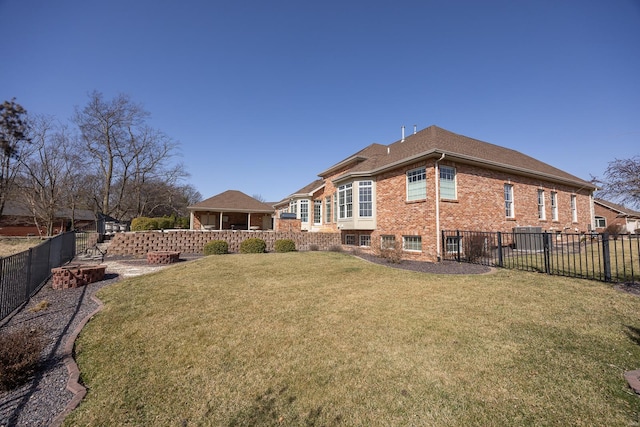 back of property featuring a yard, a patio, brick siding, and a fenced backyard