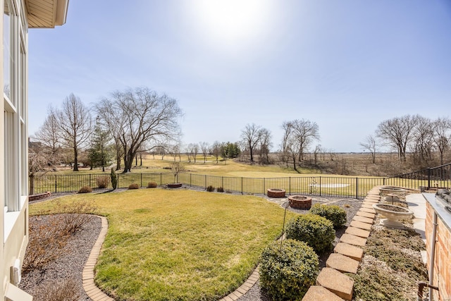 view of yard with a rural view, a fenced backyard, and an outdoor fire pit