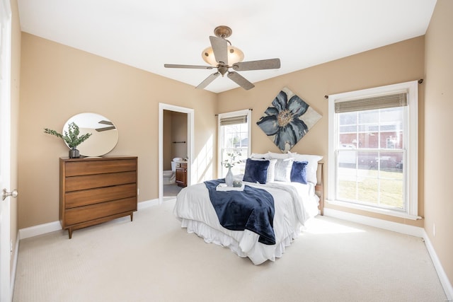 bedroom featuring baseboards, light colored carpet, ceiling fan, and ensuite bathroom