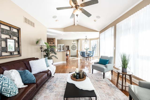 living area featuring visible vents, vaulted ceiling with beams, baseboards, ceiling fan with notable chandelier, and wood finished floors